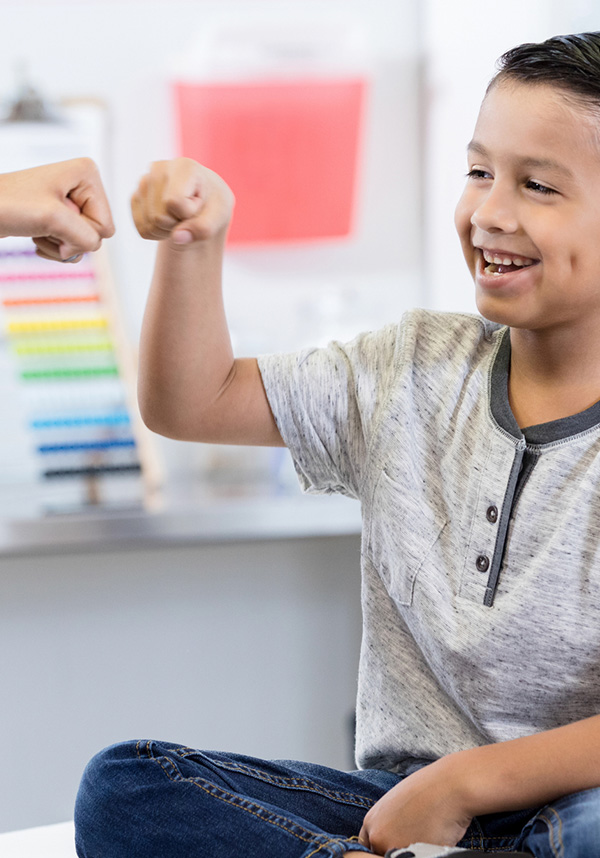 Healthy Blue Choices Hero A child smiling in doctors office, fist bumping provider